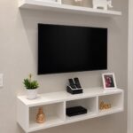 White floating shelf under a wall-mounted television with decorative home accessories