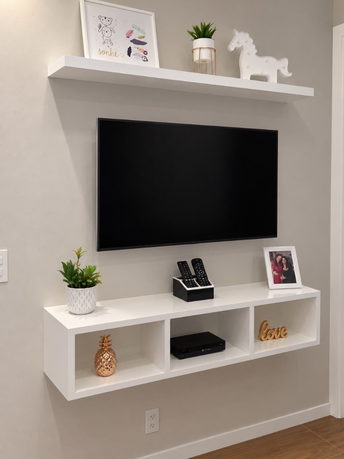 White floating shelf under a wall-mounted television with decorative home accessories