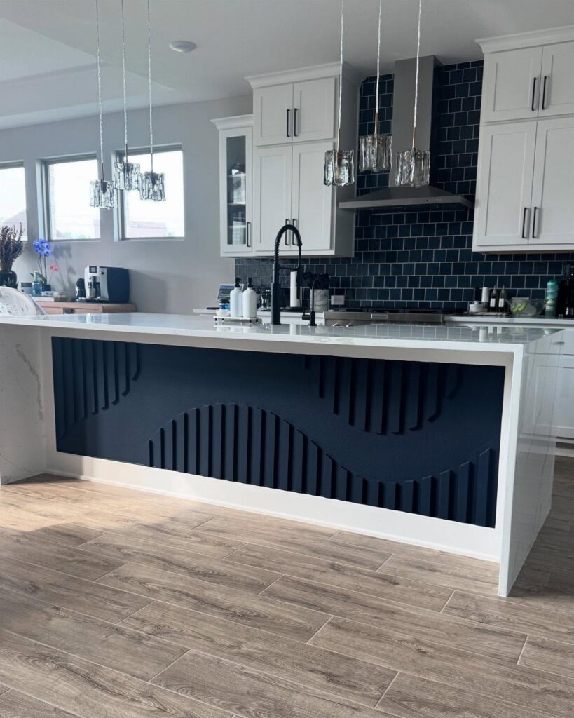 Kitchen island with a navy blue slatted back panel and white marble countertop.