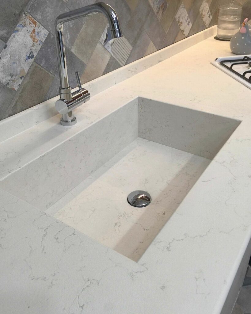 White quartz kitchen countertop with an integrated rectangular undermount sink and chrome faucet