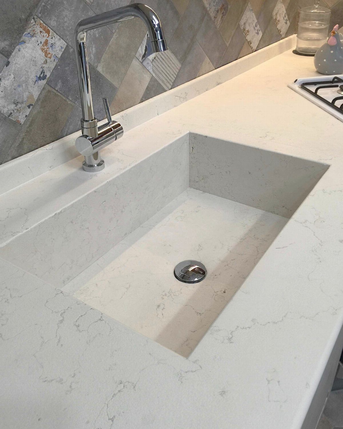 White quartz kitchen countertop with an integrated rectangular undermount sink and chrome faucet