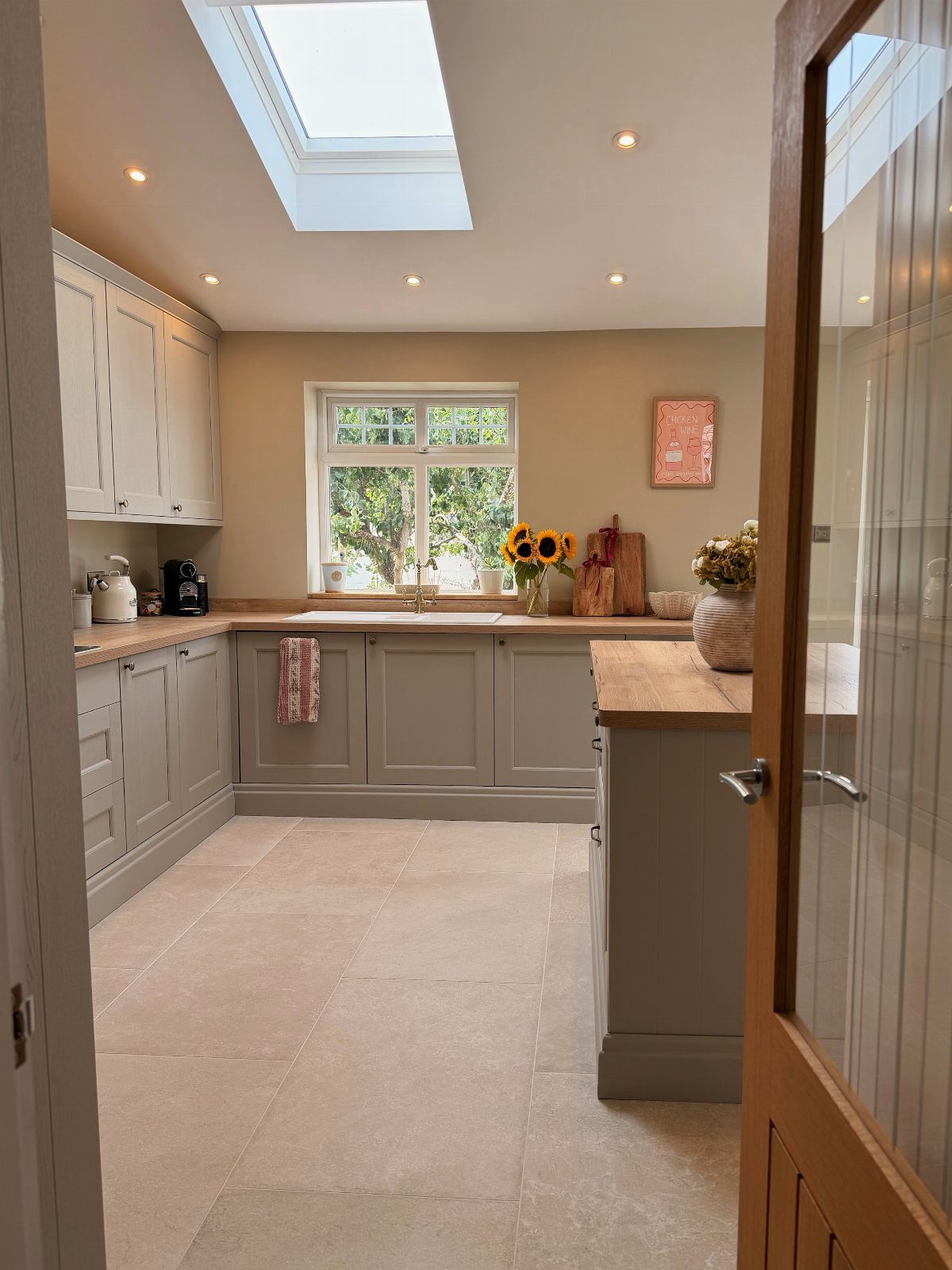 Small kitchen with grey cabinets, recessed ceiling spotlights, and a bright skylight.